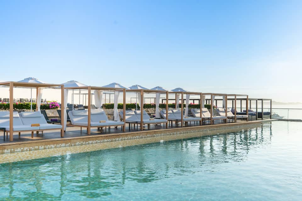 Resort poolside with wooden canopy loungers and turquoise water
