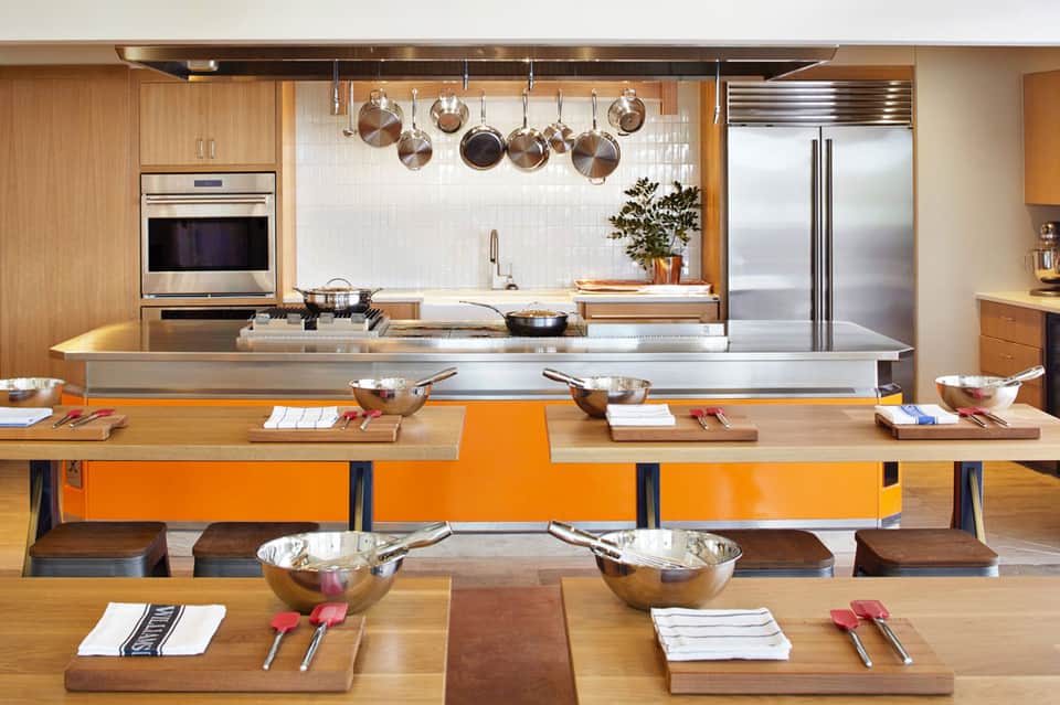 Luxury modern kitchen with wood cabinetry, stainless steel appliances, and hanging copper cookware