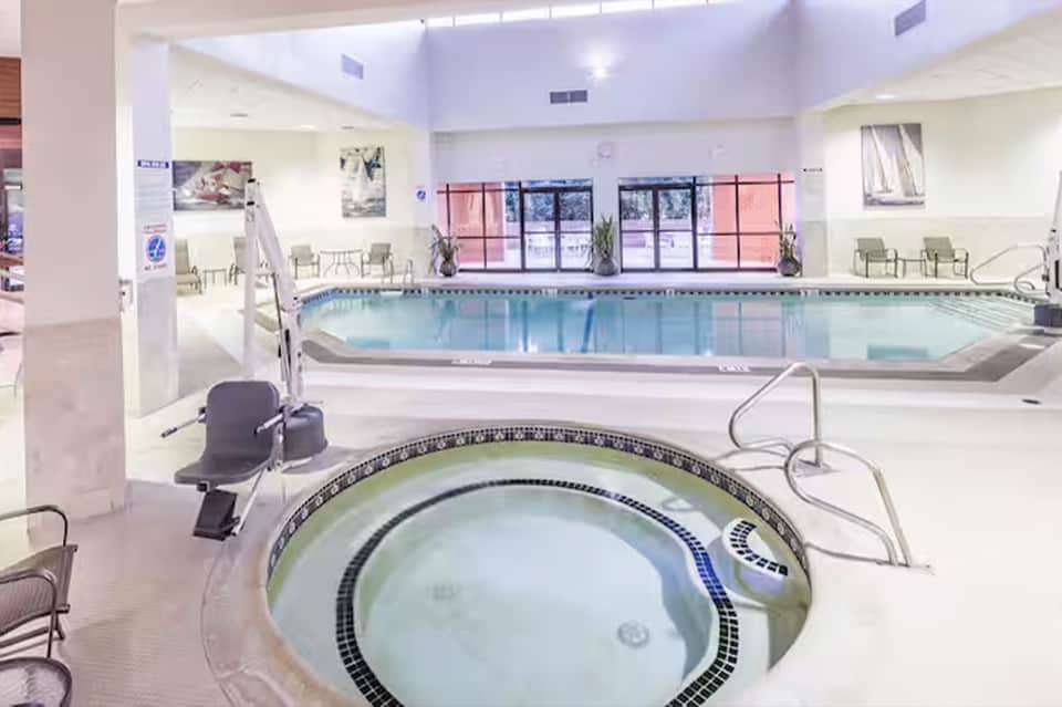 Indoor aquatic facility with indoor pool, hot tub, and spa chairs under skylights