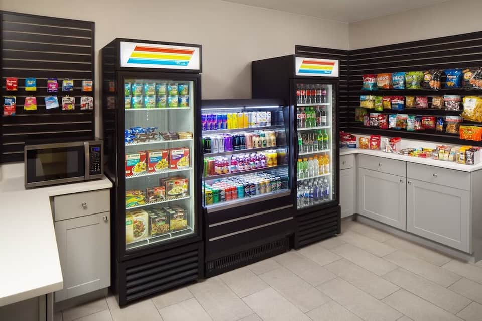 Hotel convenience store with refrigerated beverage cases and shelves stocked with snacks and drinks