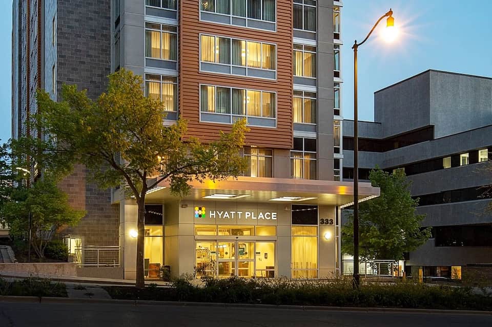 Hyatt Place hotel exterior entrance lit at dusk with modern architecture and surrounding buildings