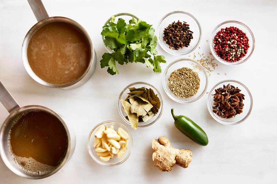 Cooking ingredients and spices in bowls including fresh cilantro, garlic, ginger, and various seasonings