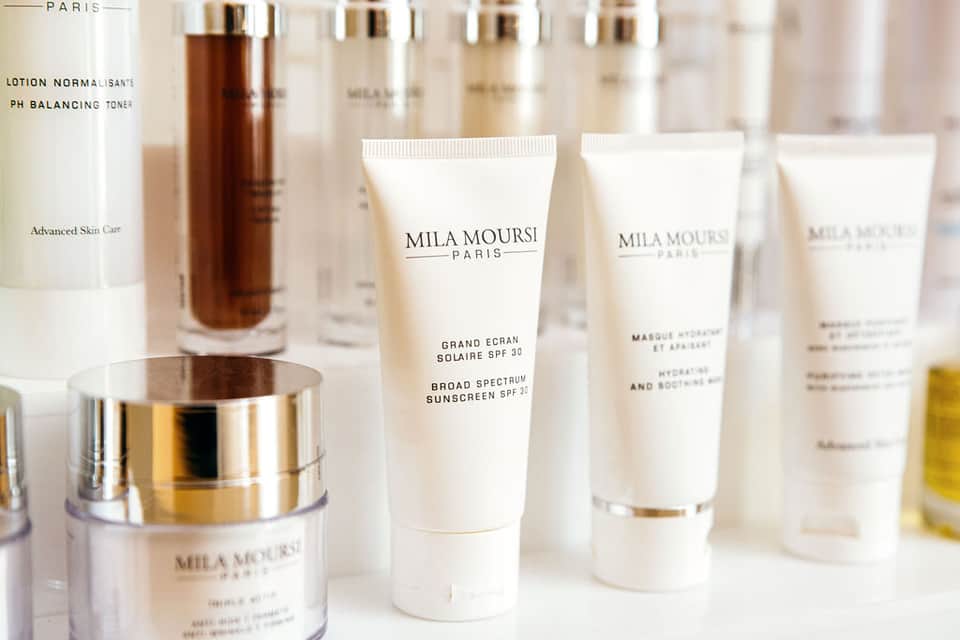 Luxury skincare products displayed including Mila Moursi Paris serums, creams, and sunscreen bottles