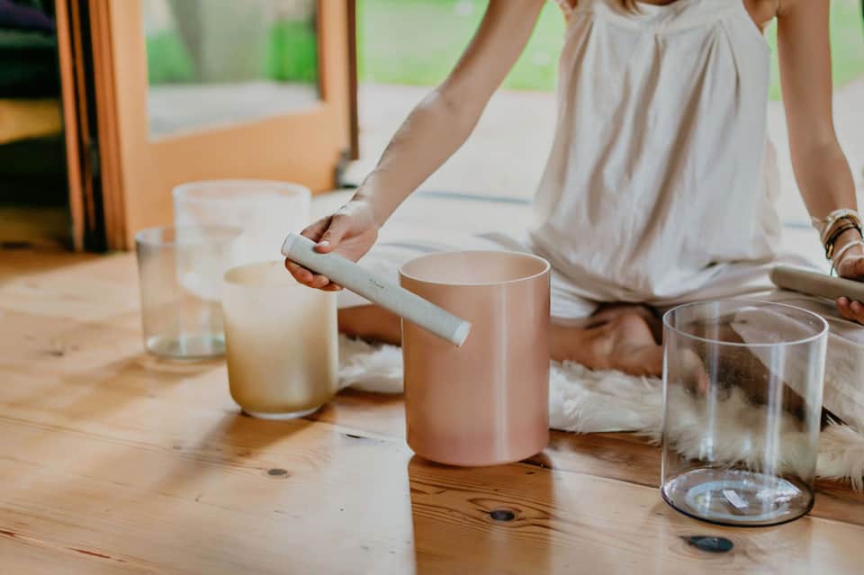 Woman's hands lighting a candle on wooden table with glass cups and minimal decor