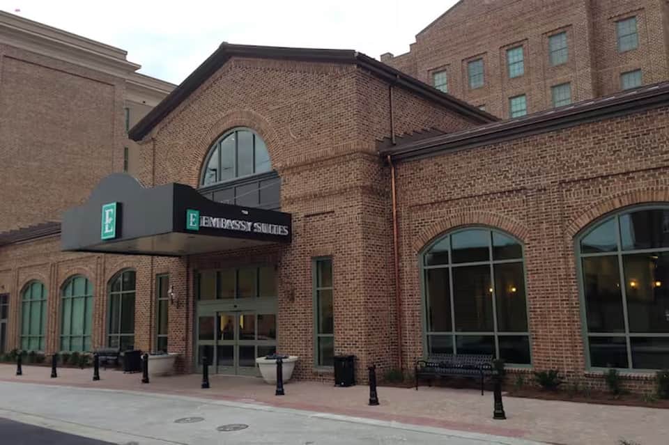 Embassy Suites hotel brick exterior with arched windows and entrance sign on brick plaza