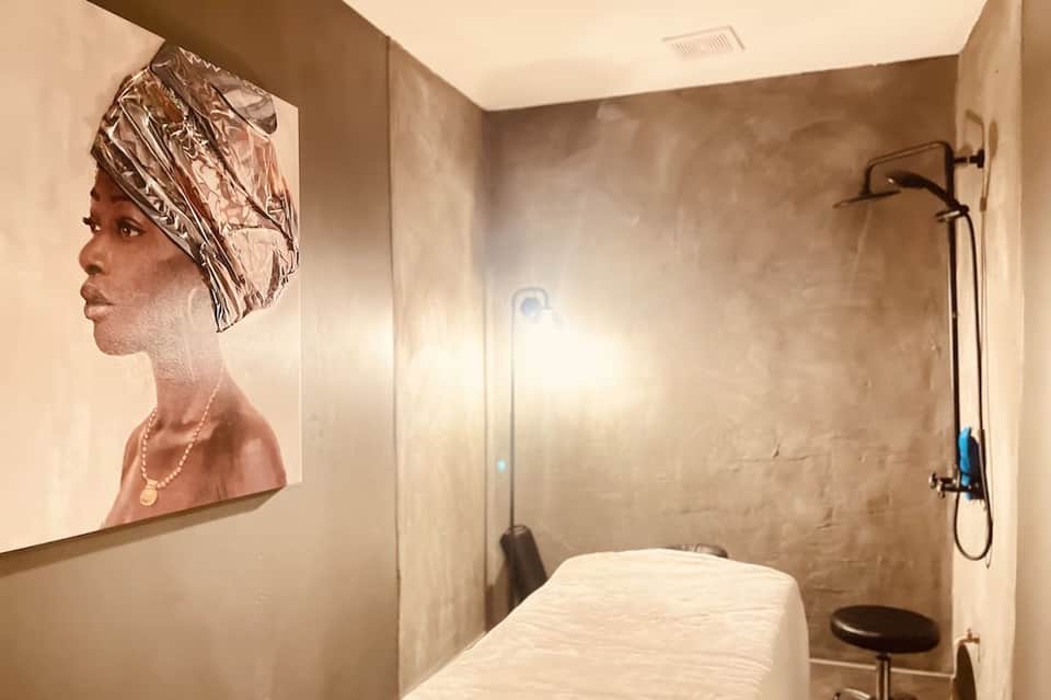Spa treatment room with massage table and artistic portrait on wall