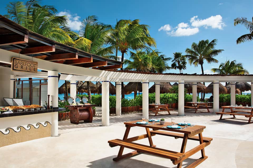 Barefoot Grill beachfront restaurant with wooden tables and thatched umbrellas