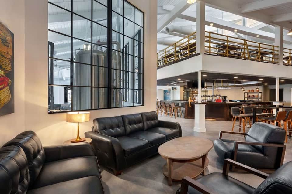 Modern hotel lobby with black leather seating, geometric wall art, and multi-level open floor plan