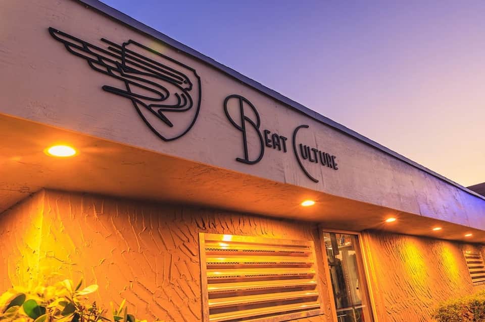 Beat Culture storefront exterior at dusk with neon sign and warm orange lighting
