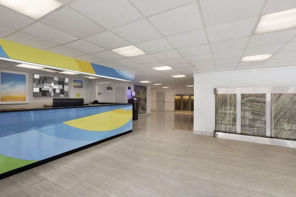 Modern hotel lobby with colorful blue and yellow reception desk and polished flooring