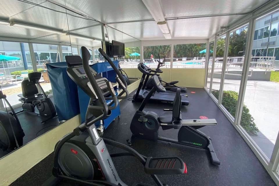 Modern fitness center with exercise bikes and elliptical machines in a bright glass-enclosed room