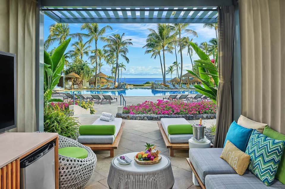 Luxury ocean-view suite interior with green accents, patio doors, and tropical landscaping