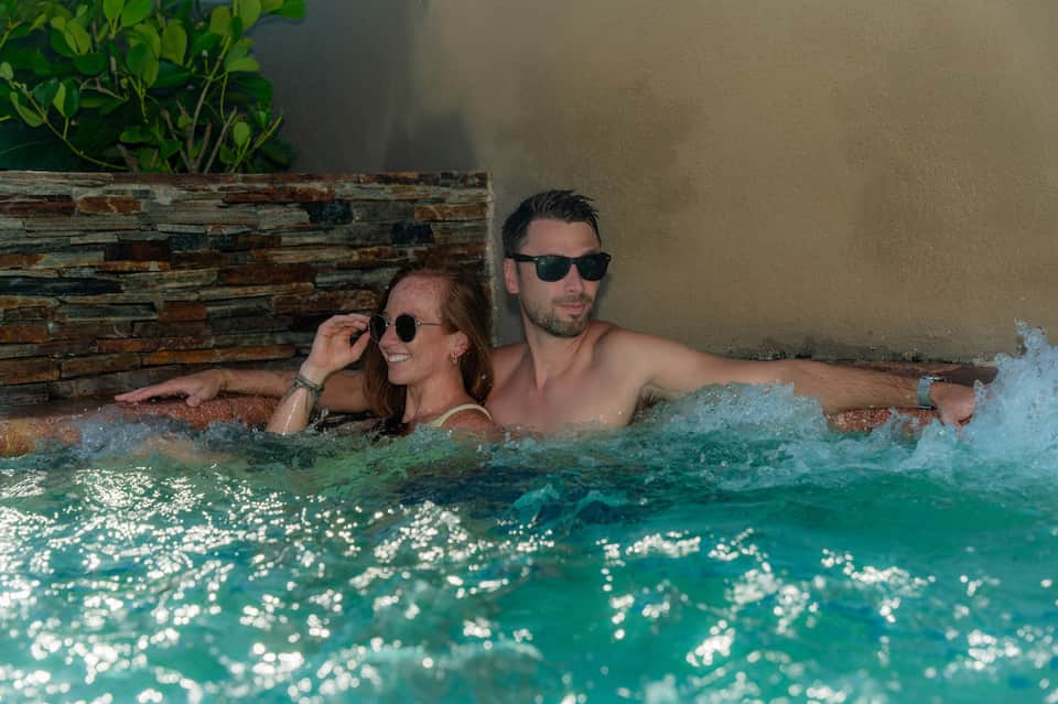 Couple enjoying hot tub spa with warm turquoise water and rustic wooden accent wall
