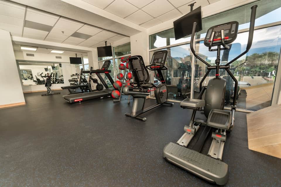 Modern fitness center with cardio equipment, exercise bikes, treadmills, and large windows overlooking mountains