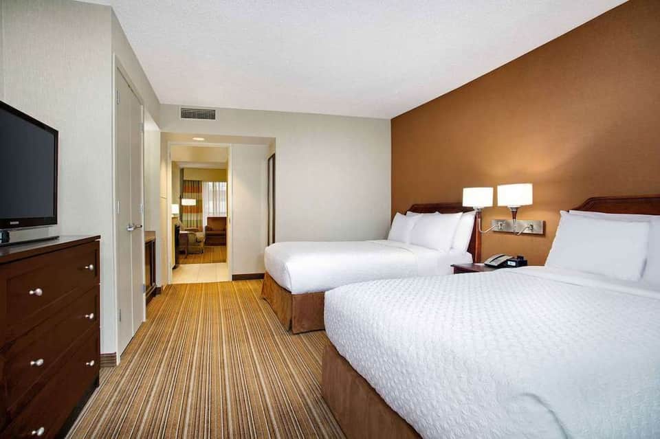 Hotel room with two queen beds, wood furnishings, and modern décor