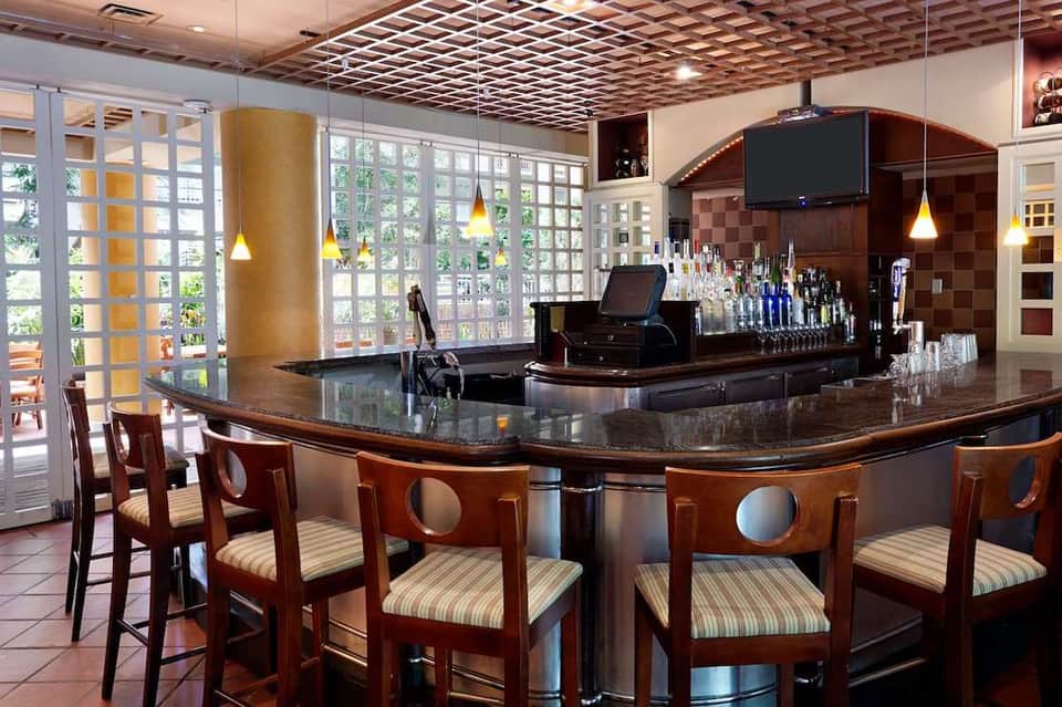 Elegant bar with curved dark wood counter, pendant lights, and gridded glass doors