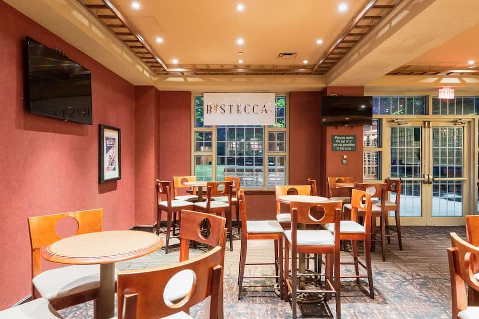 Casual dining restaurant with coral walls, wooden chairs, and white tables under wooden beamed ceiling.