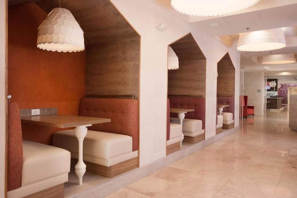 Modern spa lounge with booth seating, pendant lighting, and warm orange accent walls