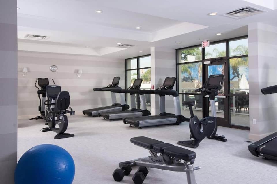 Bright fitness facility with treadmills, stationary bikes, exercise ball, and glass doors