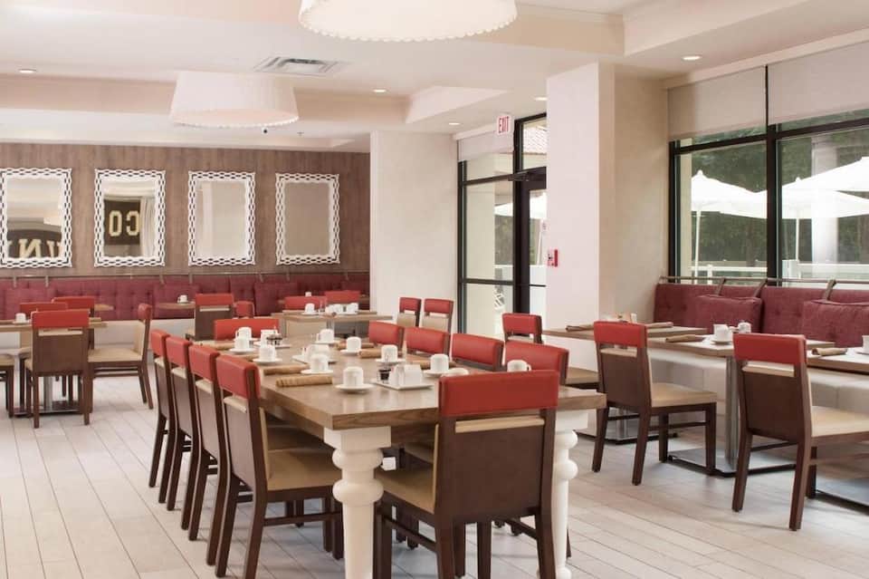 Modern dining room with white ceiling, red accent chairs, and wooden tables