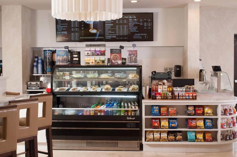 Hotel café counter with pastry display case, menu board, coffee equipment, and snack shelves