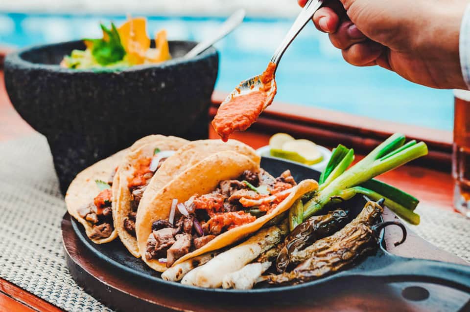Plated tacos with grilled meat and vegetables served poolside with ocean view