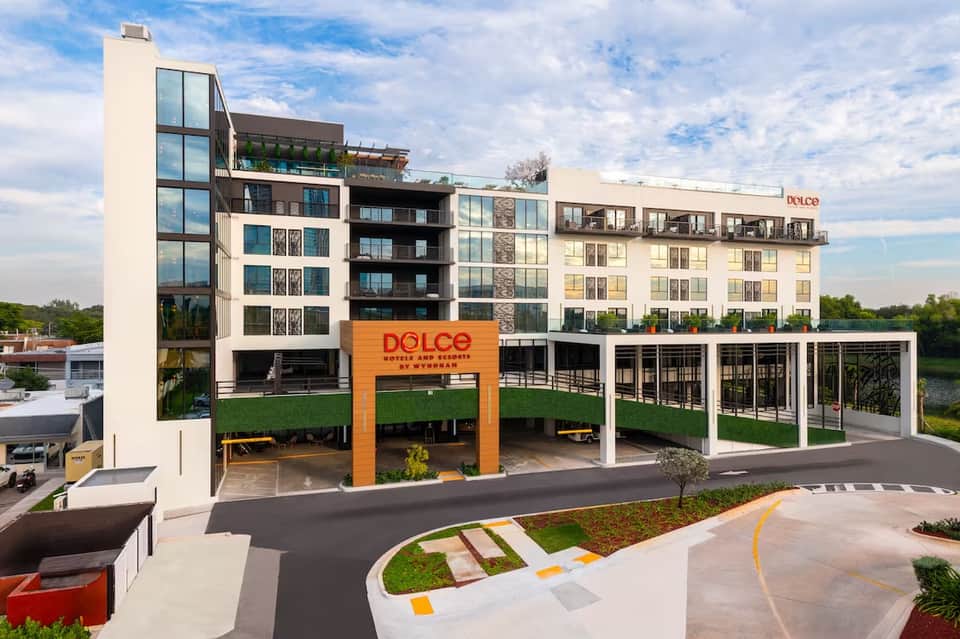 Modern mixed-use waterfront building with Dolce restaurant, orange signage, green landscaping, and residential apartments above