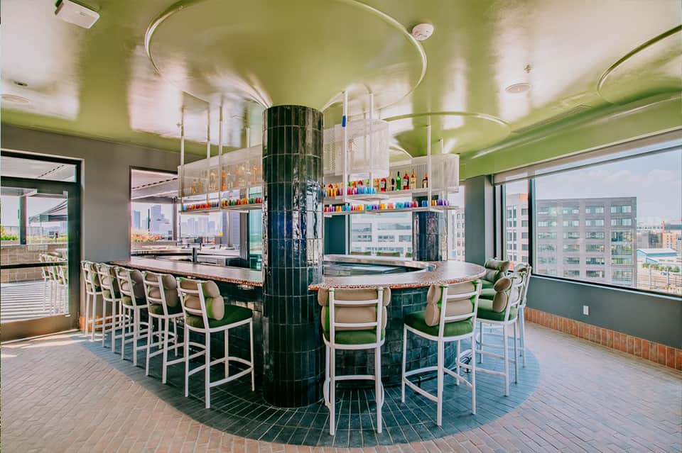Contemporary bar with green ceiling, circular counter, and colorful bottles in resort setting