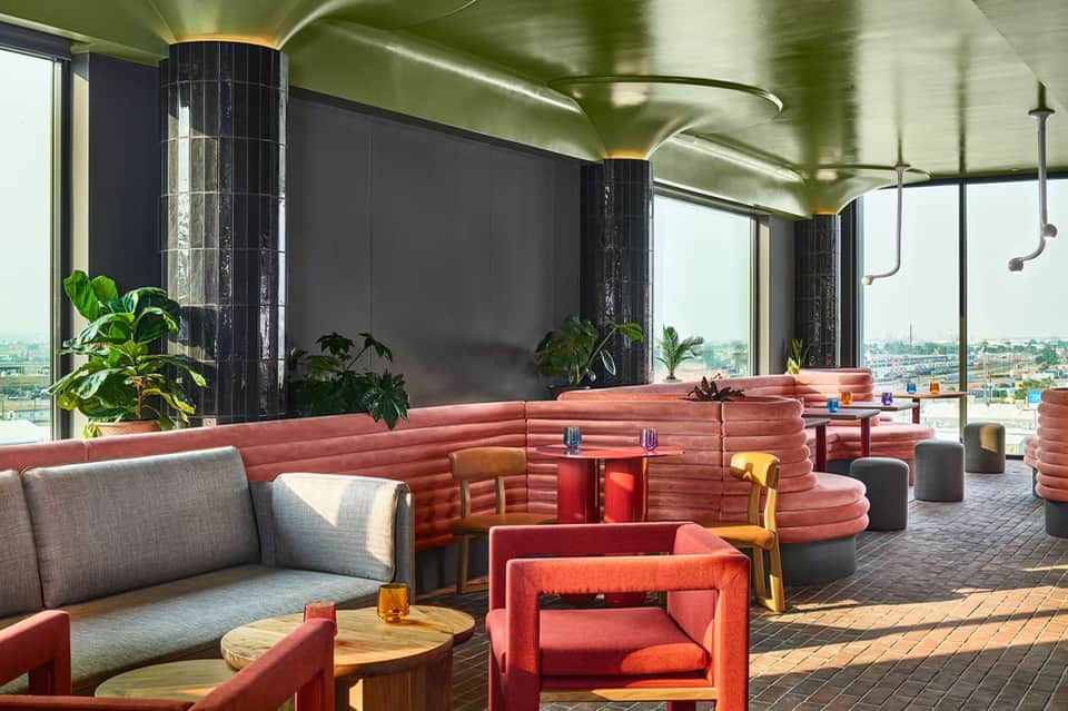 Contemporary rooftop lounge with coral seating, green ceiling, floor-to-ceiling windows overlooking cityscape