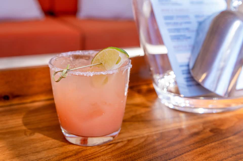 Grapefruit margarita cocktail with salt rim and lime garnish on wooden bar
