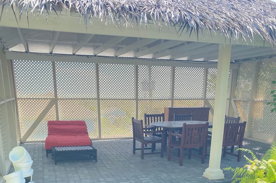 Covered patio with lattice screening, featuring a red futon and dark wooden dining furniture