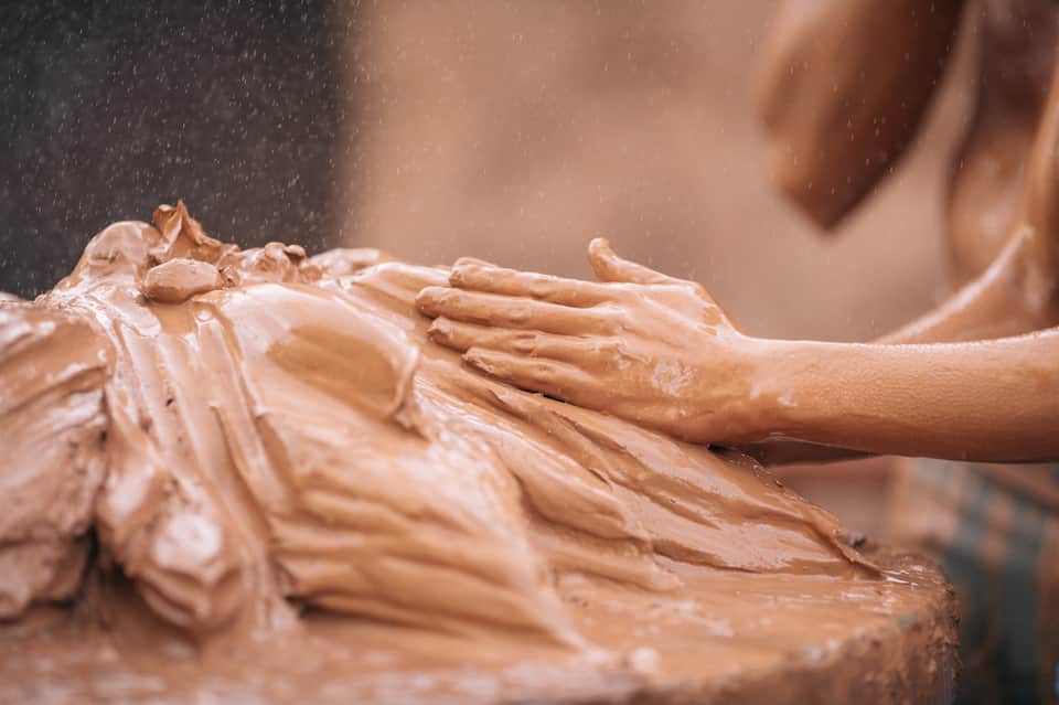 Hands applying clay or spa treatment to person's back during wellness therapy