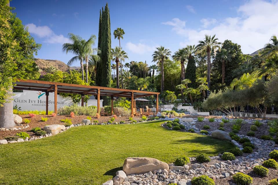 Glen Ivy Hot Springs with wooden pergola, manicured lawn, palm trees, and desert landscape