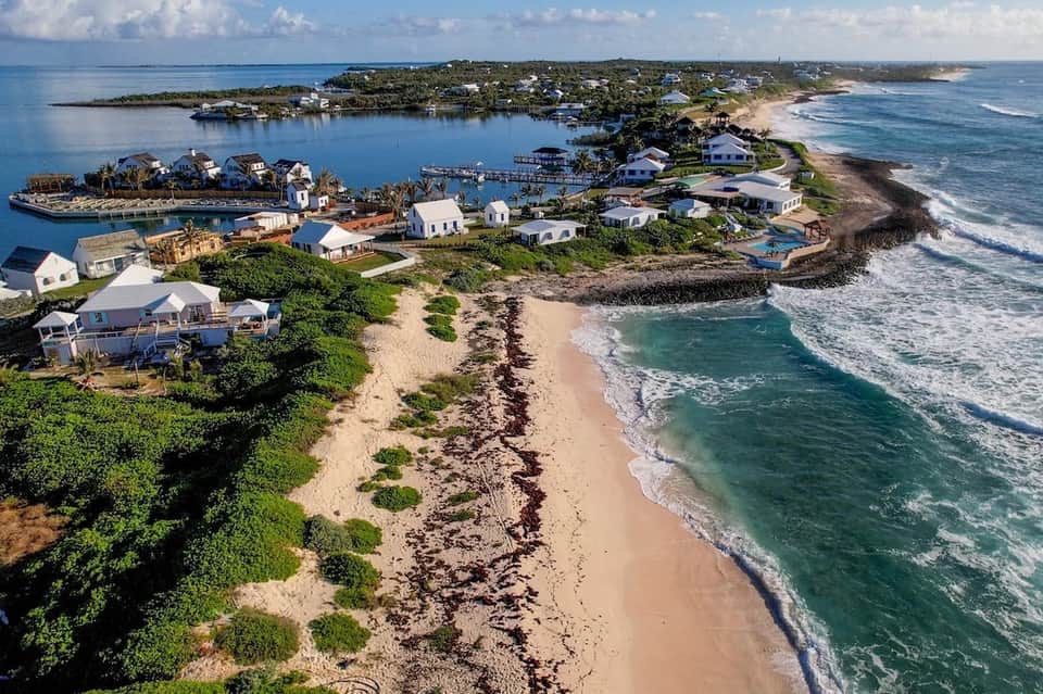 Aerial view of beachfront residential community with white homes, sandy beach, and turquoise ocean