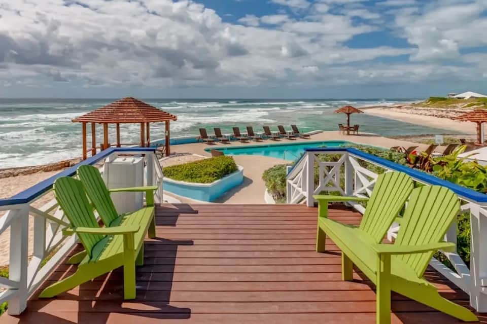 Beachfront resort deck with lime green Adirondack chairs, pool, and ocean view