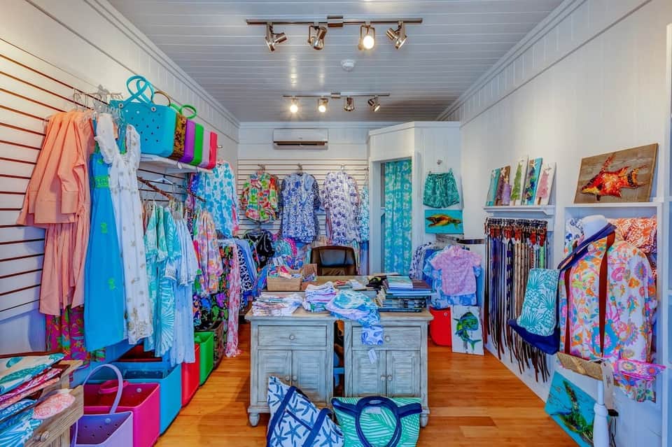 Retail boutique interior with colorful beachwear displayed on walls and clothing racks