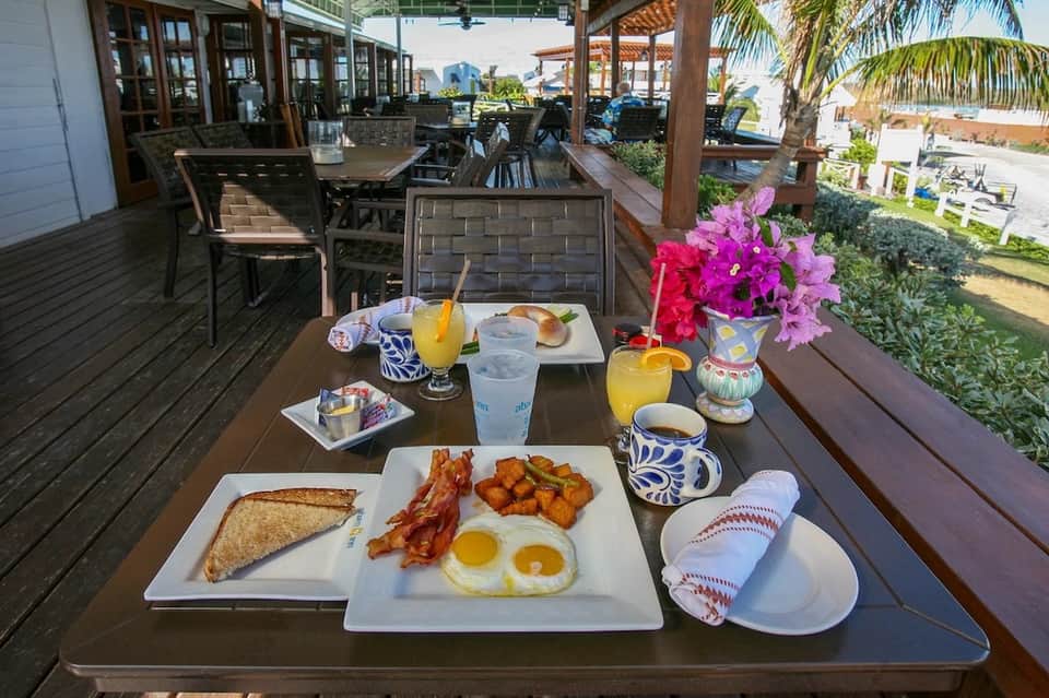Beachfront restaurant terrace breakfast spread with eggs, bacon, toast, and ocean views