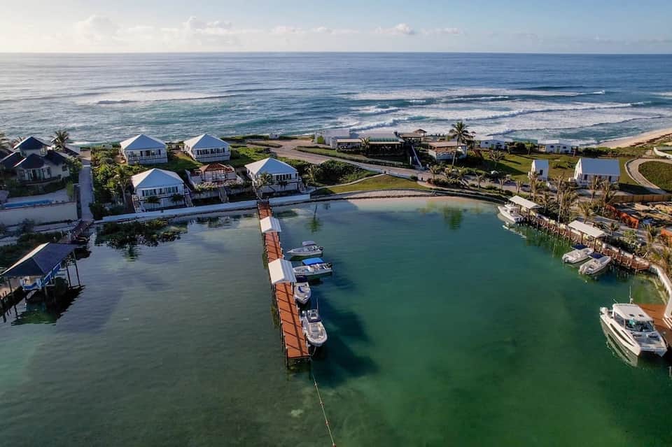 Aerial view of waterfront cottages with dock, boats, and sandy beach