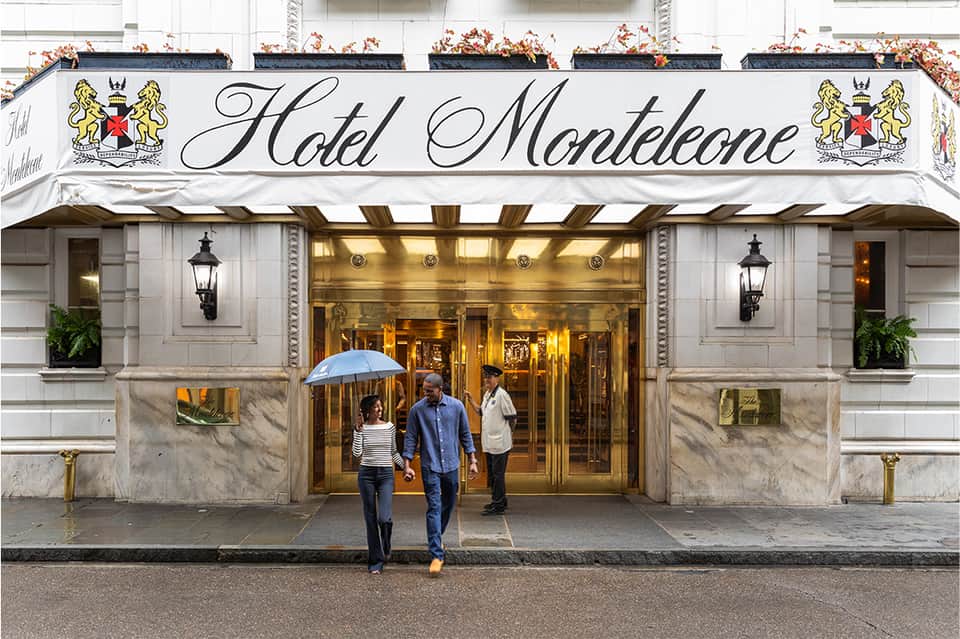 Hotel Montelcone entrance with elegant white awning, brass fixtures, and guests with umbrella on rainy street