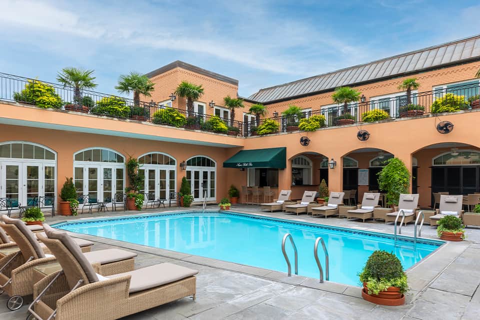 Indoor courtyard pool surrounded by arched colonnade, loungers, and multi-story hotel building