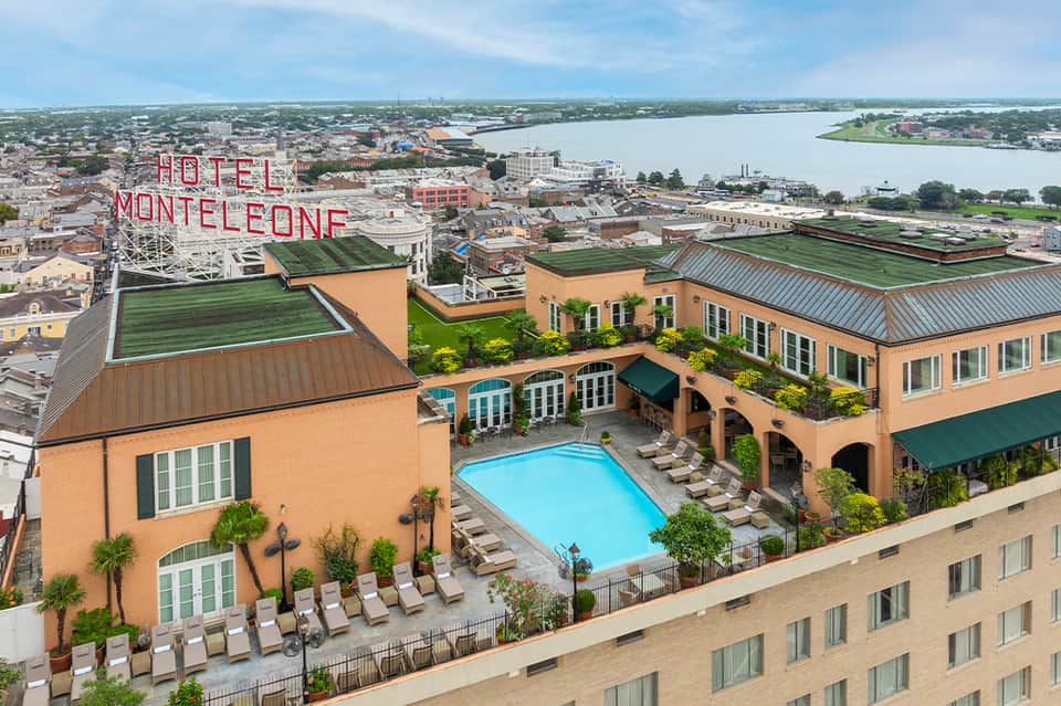 Aerial view of Hotel Monteleone with pool, green roofs, and river in background