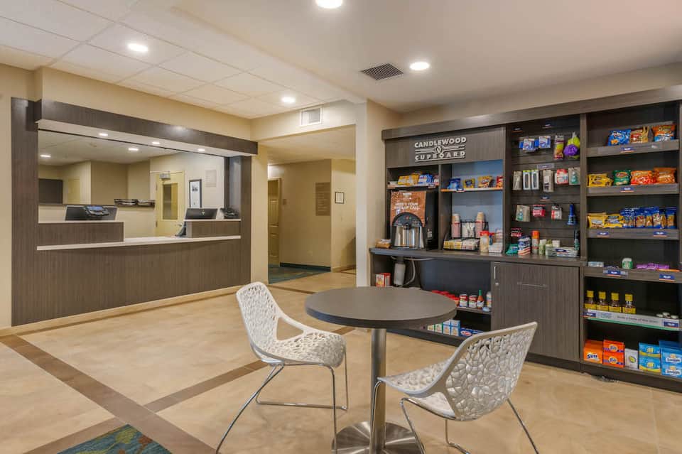 Hotel lobby with reception desk, seating area, and retail shelving display