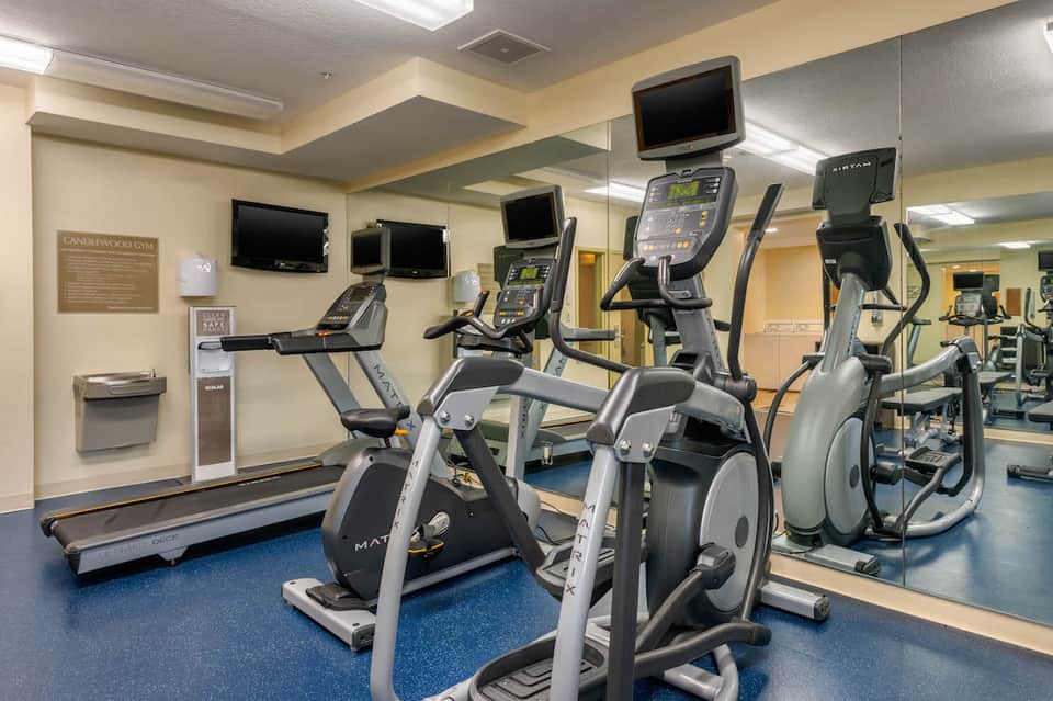 Fitness center with exercise equipment including treadmills, stationary bikes, and elliptical machines with TV screens