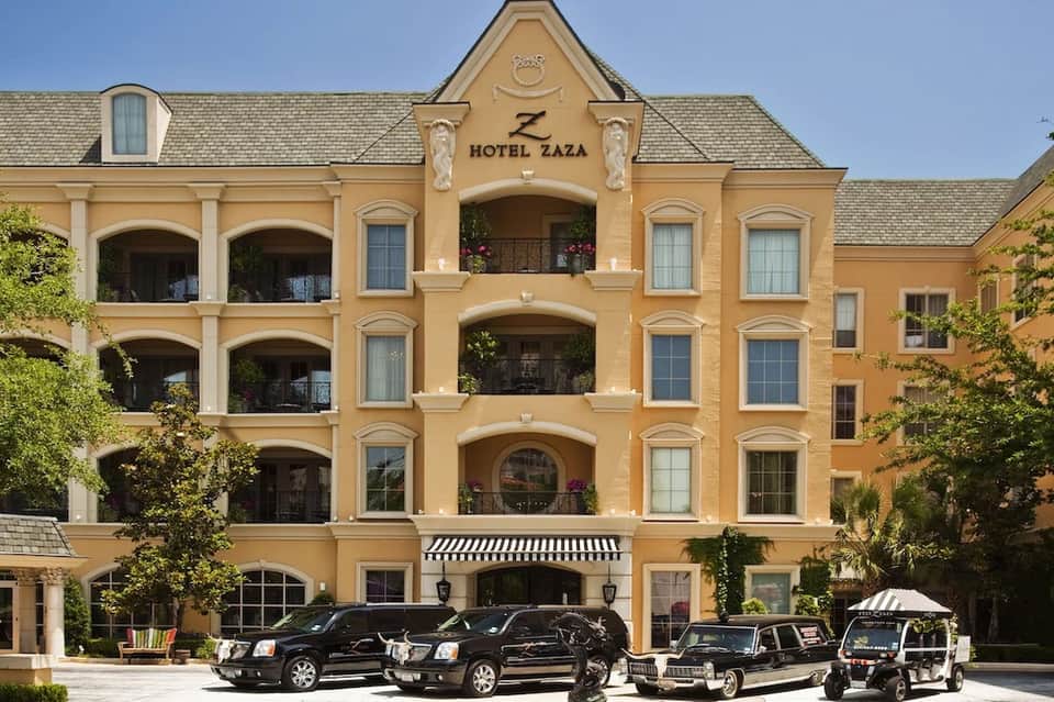 Ornate yellow Hotel Zaza facade with classic architecture and vintage cars parked outside