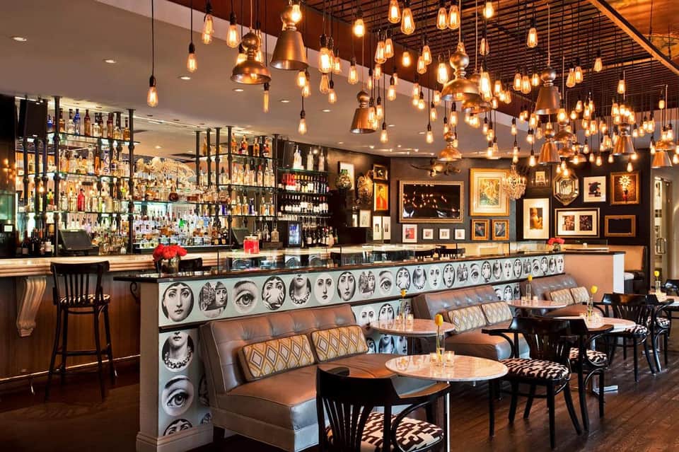 Upscale bar lounge with hanging copper pendant lights, leather seating, and decorative artwork