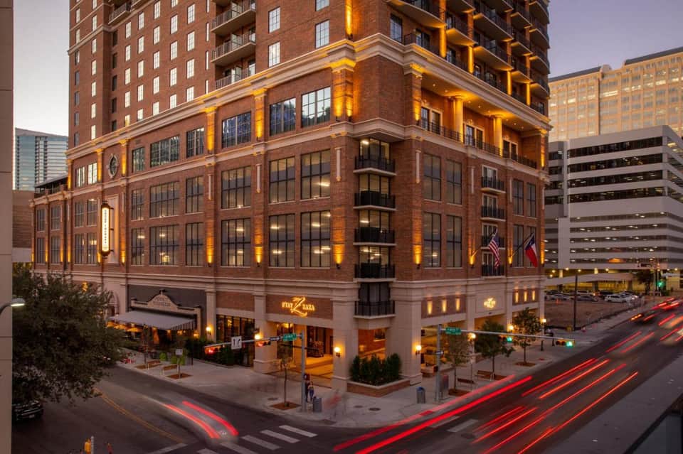 Historic brick building illuminated at dusk with ground-floor retail in urban downtown setting