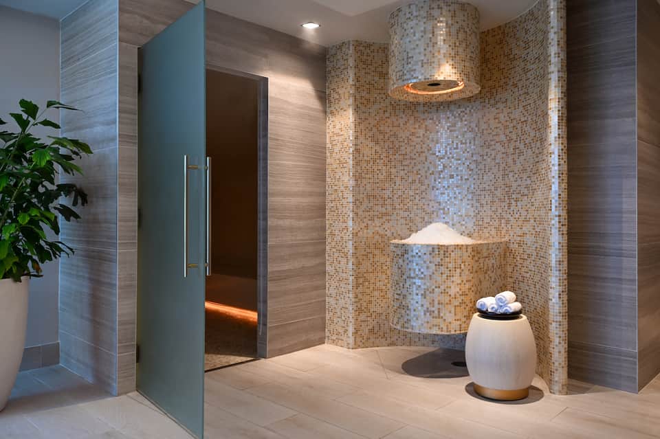 Modern bathroom with rainfall showerhead, mosaic tile walls, neutral tones, and ambient lighting