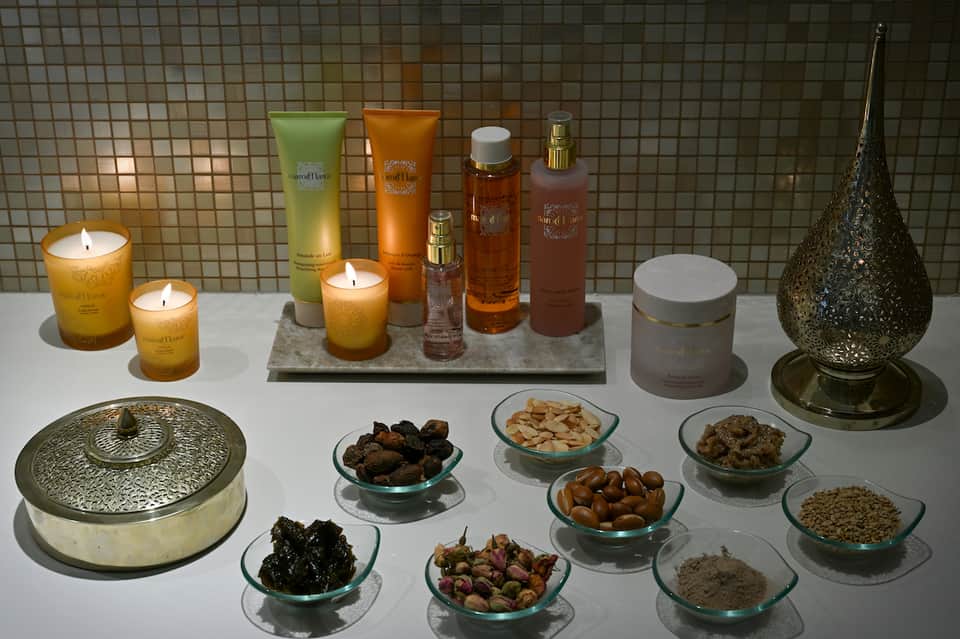Luxury spa products display with scented candles, bath oils, and aromatherapy bowls on white surface