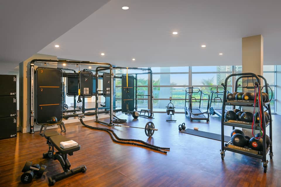 Upscale fitness center with modern gym equipment, large windows, and scenic views of landscape