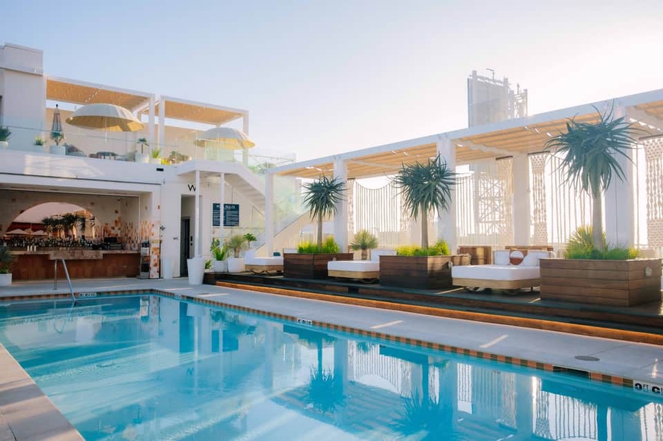 Modern rooftop pool with white pergolas, lounge seating, and contemporary architectural design